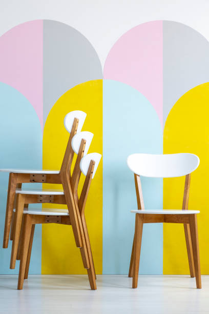 istock Classic, wooden dining chairs with white elements in front of geometric decorations in a colorful room interior. Real photo. 1044796426