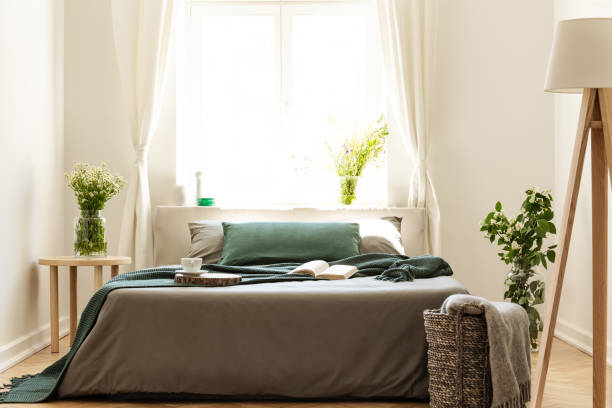 istock Eco friendly bedroom interior with a bed dressed in gray and green bedding. Sunny window as a background. Real photo. 1044799658