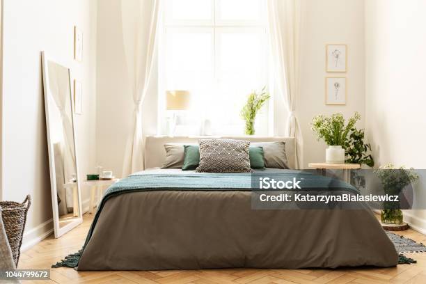 Beige Green And Gray Bedroom Interior In A Tenement House With A Bed Against A Sunny Window And Bunches Of Wild Flowers Real Photo Stock Photo - Download Image Now