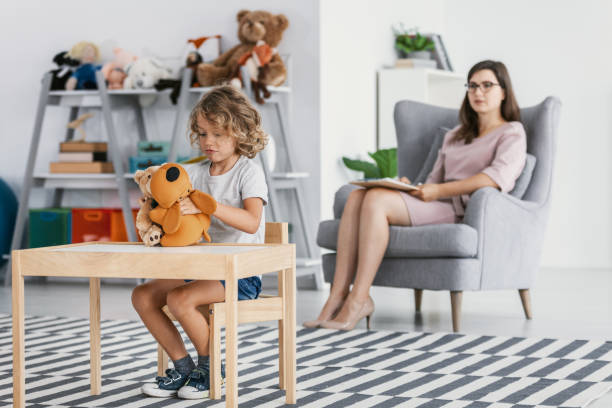 istock Unbearable boy playing with plush toy while psychotherapist analysing his behavior 1044803722