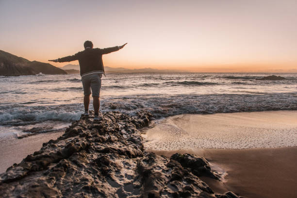 istock Young man balancing on rocks at beach 1044807884