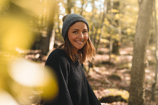 A beautiful woman is out in a forest in Sweden, picking mushrooms and stopping for a break to drink coffee on a sunny autumn day.