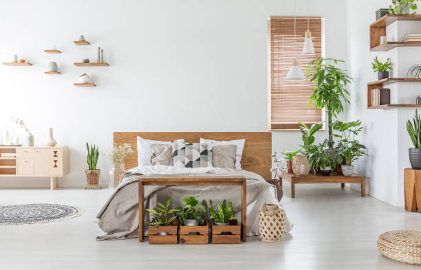 istock Bed with wooden headboard in white spacious bedroom interior with cupboard and plants. Real photo 1044809724