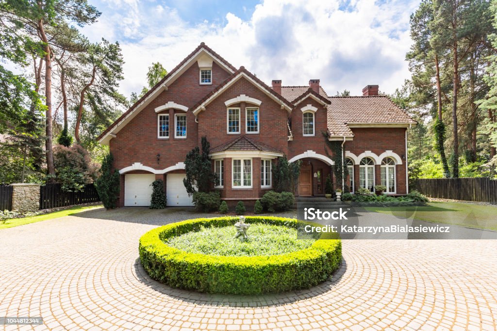 Front view of a driveway with a round garden and big, english style house in the background. Real photo Domestic Life Stock Photo