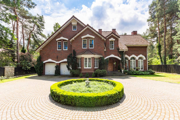 Front view of a driveway with a round garden and big, english style house in the background. Real photo Front view of a driveway with a round garden and big, english style house in the background. Real photo the hamptons photos stock pictures, royalty-free photos & images
