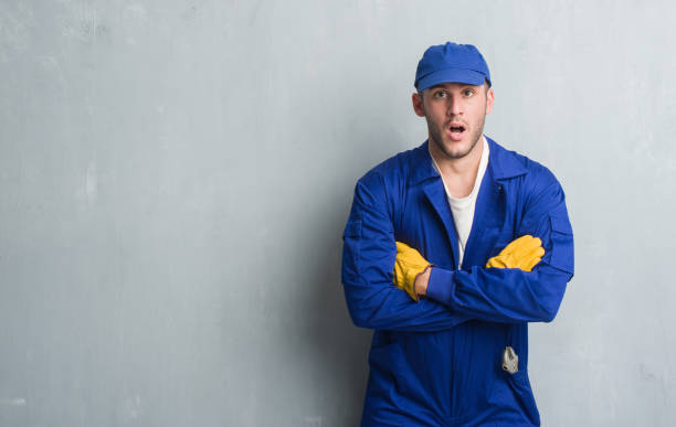 istock Young caucasian man over grey grunge wall wearing mechanic uniform scared in shock with a surprise face, afraid and excited with fear expression 1044816232