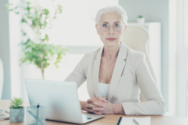 istock Gray-haired beautiful stylish old serious self-confident lady office executive working sitting in front of laptop, at workplace workstation 1044820968