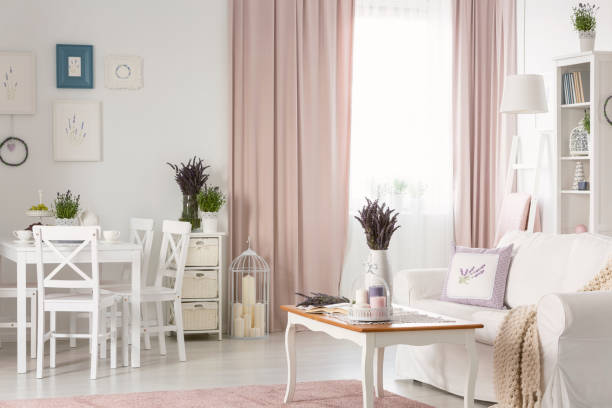 istock White chairs at dining table near posters in flat interior with pink drapes and settee. Real photo 1044824816