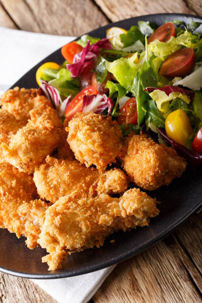 istock fried in breaded chicken wings and fresh vegetable salad close-up on a table. vertical 1044827692