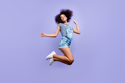 Bottom view portrait of crazy positive girl in jeans outfit jumping in air enjoying daydream having weekend vacation holiday isolated on violent background. Luck success concept