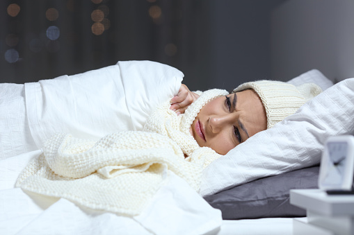 Angry woman suffering cold complaining in a bed in winter