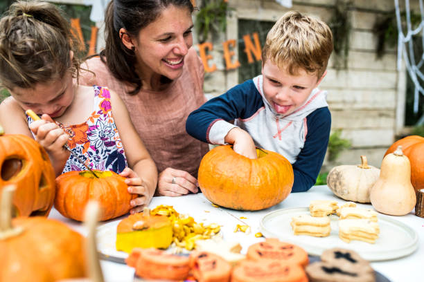 istock Young kids carving Halloween jack-o'-lanterns 1044832550