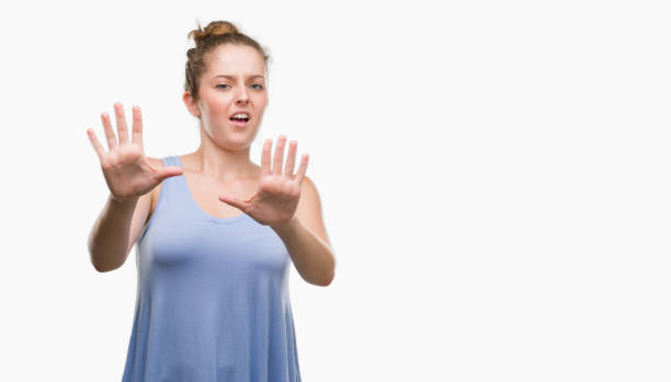 istock Young blonde woman afraid and terrified with fear expression stop gesture with hands, shouting in shock. Panic concept. 1044843074
