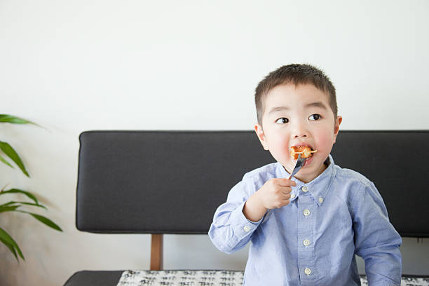 Japanese child eating on couch stock photo