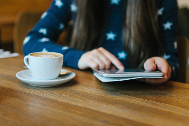 девушка в кафе пьет кофе и пользуется планшетом - e reader digital tablet cafe reading стоковые фото и изображения