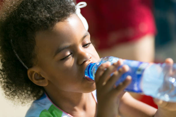 istock A black child eagerly drinks water from a bottle. 1044866774