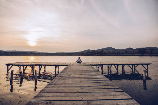 One woman, meditating by the lake outdoors alone.