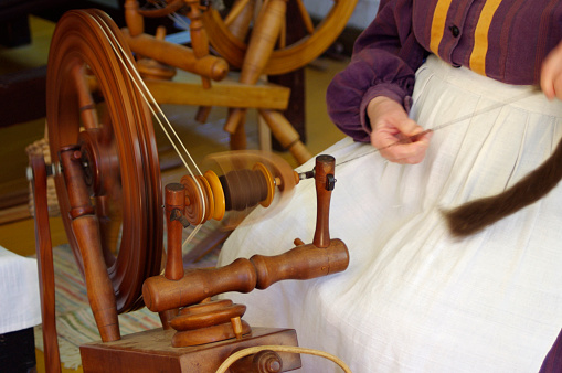 Pioneer lady using Old fashioned wooden spinning wheel