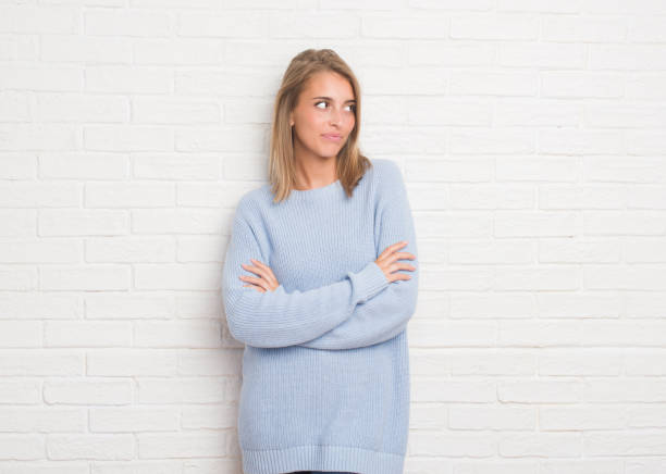 istock Beautiful young woman over white brick wall smiling looking side and staring away thinking. 1044871956