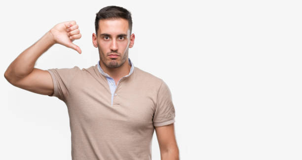 istock Handsome young man with angry face, negative sign showing dislike with thumbs down, rejection concept 1044876028