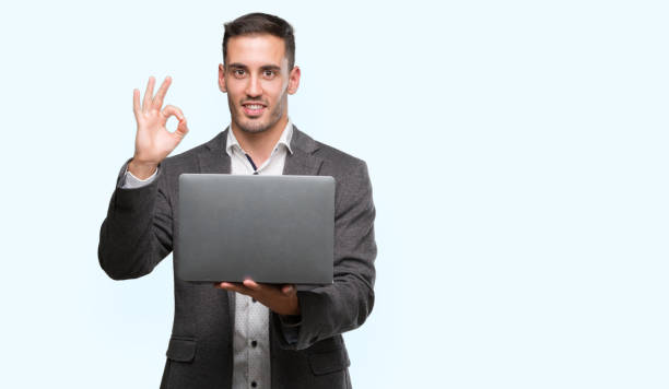 istock Handsome young man using computer laptop doing ok sign with fingers, excellent symbol 1044876134