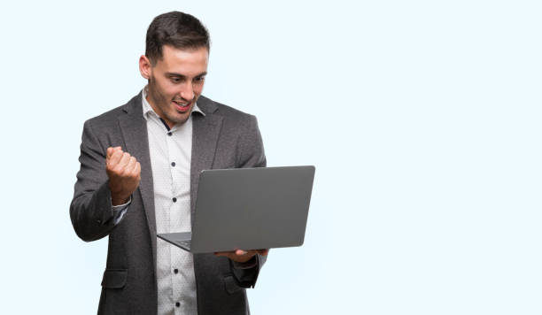 istock Handsome young man using computer laptop screaming proud and celebrating victory and success very excited, cheering emotion 1044876172