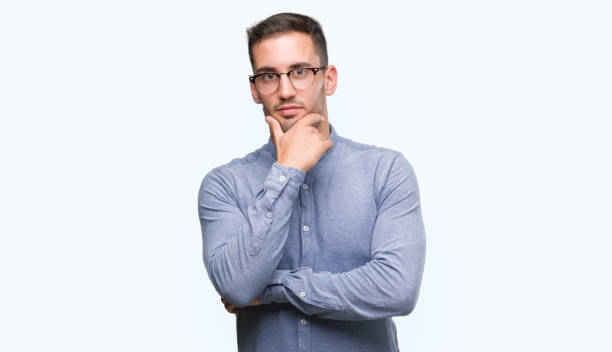 istock Handsome young elegant man wearing glasses looking confident at the camera with smile with crossed arms and hand raised on chin. Thinking positive. 1044878960