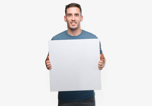 istock Handsome young man holding advertising banner with a happy face standing and smiling with a confident smile showing teeth 1044879426