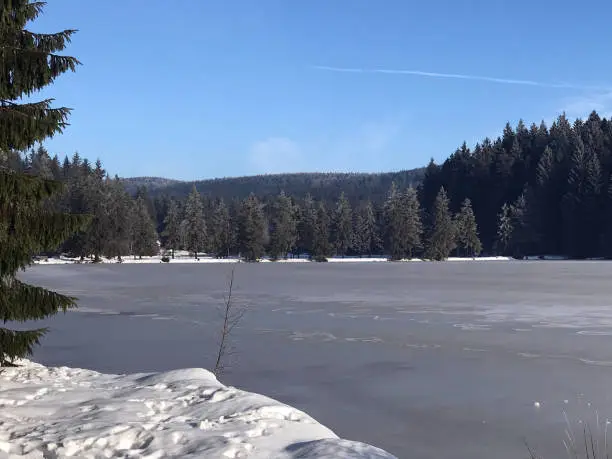 Winter landscape on the lake with: blue sky, ice surface, sunshine and snow
