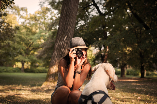Young woman taking picture of her dog outdoors.