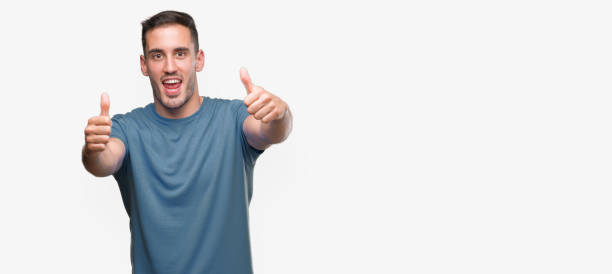 istock Handsome young casual man approving doing positive gesture with hand, thumbs up smiling and happy for success. Looking at the camera, winner gesture. 1044879710