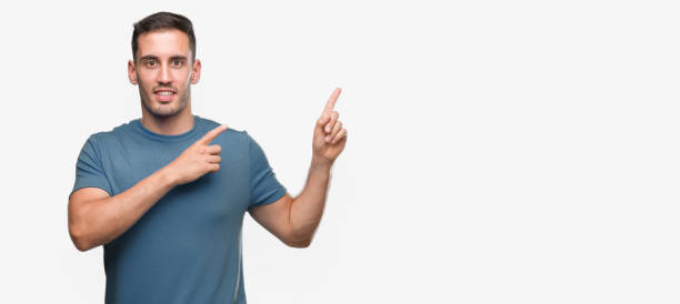 istock Handsome young casual man smiling and looking at the camera pointing with two hands and fingers to the side. 1044879824