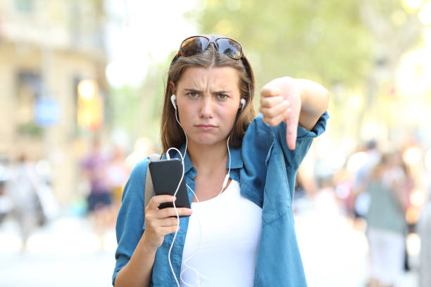 molesta chica escuchando música con los pulgares hacia abajo - escape from it all audio fotografías e imágenes de stock