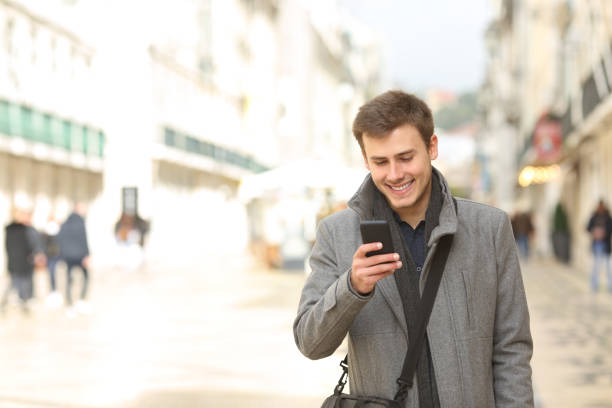 istock Man walking using a smart phone in winter in the street 1044896720