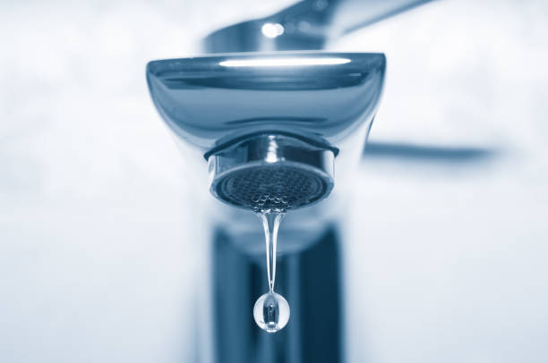 istock Tap and water drop close up on blue background 1044896748