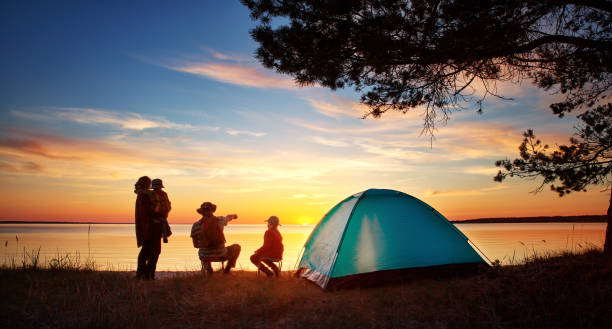 Family resting with tent in nature at sunset Family resting with tent in nature at sunset. Woman, man and children near seaside family camping stock pictures, royalty-free photos & images