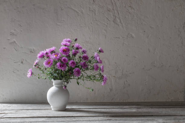 istock violet flowers in white vase on old background 1044904960
