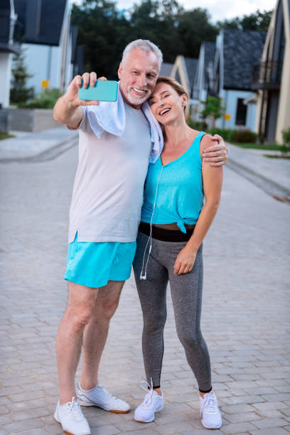 istock Bearded smiling man hugging his slim wife while making photo after running 1044907646