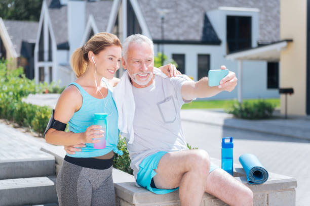 istock Bearded mature man holding his blue phone while making selfie with wife 1044907654