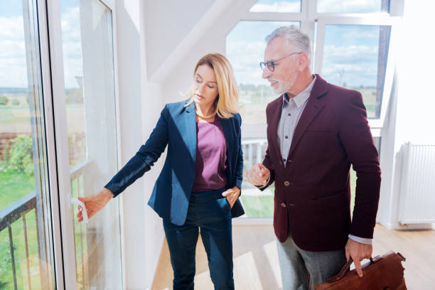 istock Experienced female estate agent showing window view her rich client 1044907712