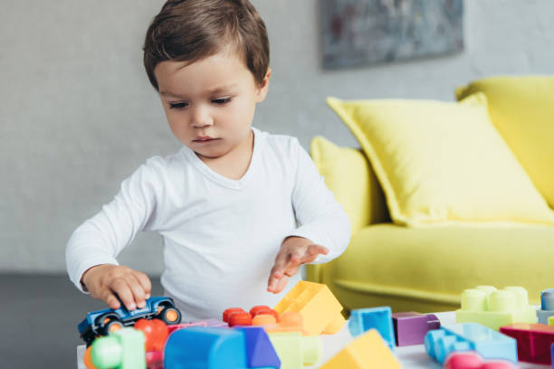 istock cute kid playing with toy car and colorful constructor blocks at home 1044927484
