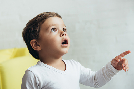 portrait of little shocked boy pointing and looking up