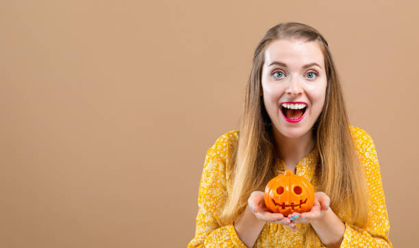 istock Young woman with a halloween pumpkin 1044935838