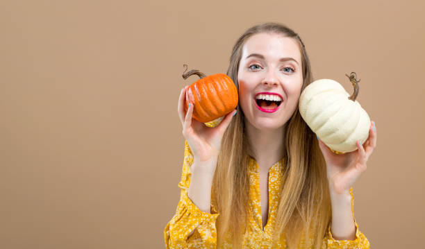 istock Young woman holding pumpkins 1044935848