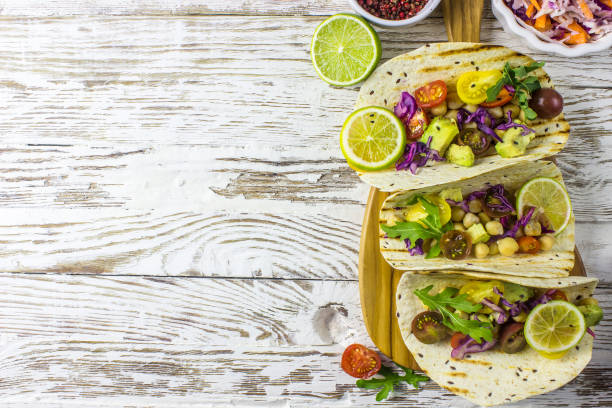 Healthy corn tortillas with chickpeas, tomatoes, avocado, fresh arugula, limes