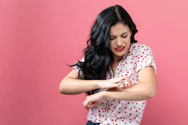 Photo of Young woman scratching her itchy arm.