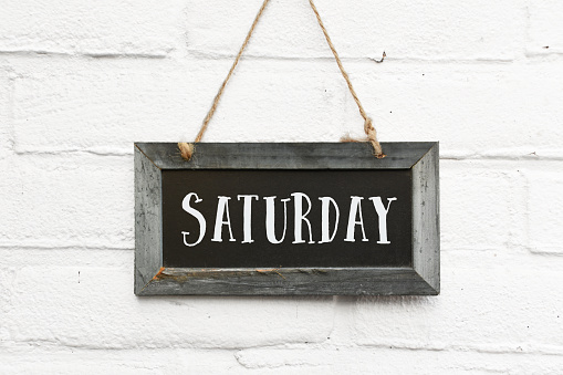 Hello saturday text on hanging board white brick outdoor wall