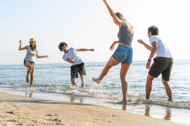 istock Group Of Friends Run Through Waves Together On Beach Vacation. 1044961126