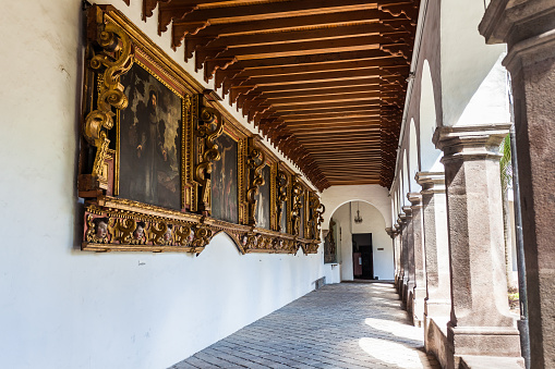 Quito, Ecuador, July 2018: Hallways of the inner courtyard of the Santo Domingo convent where you can see the arches and stone columns and the colonial pictorial art