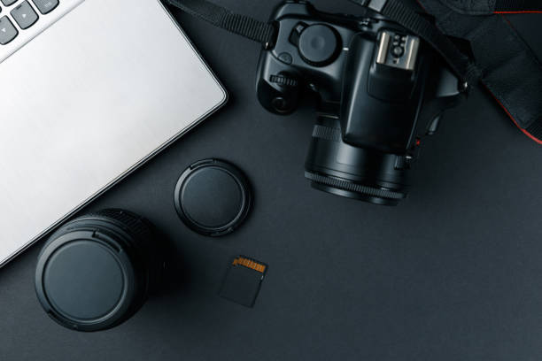 istock Work space on black table of photographer. Minimal workspace with Laptop, camera and lens copy space on dark background. Modern and elegant. Top view. Flat lay style. Close up. 1044967846
